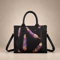 Black handbag with colourful feather motifs on a warm ivory studio background