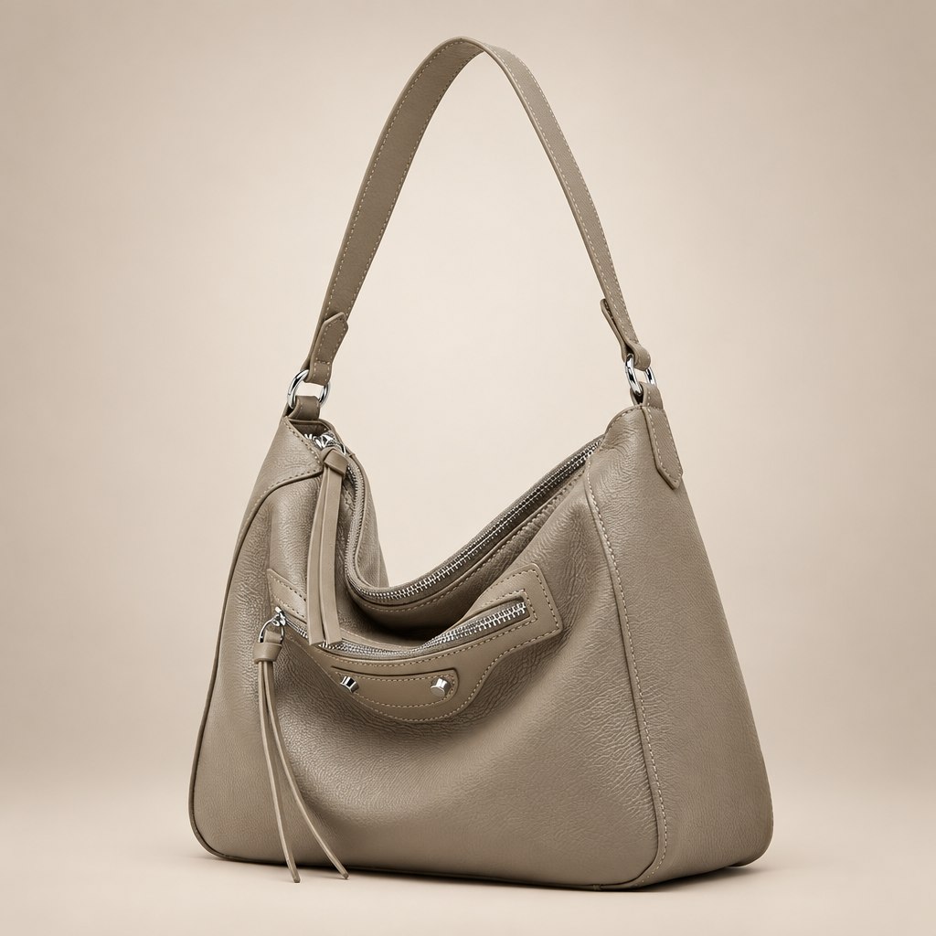 Taupe slouch handbag with silver zips on a warm ivory studio background