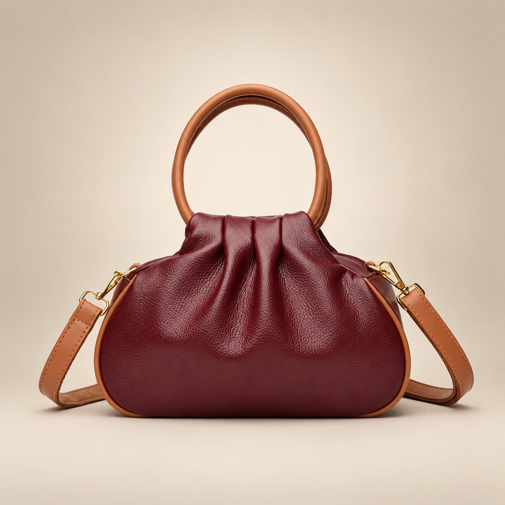 Wine red pleated bag with tan round handles on a warm ivory studio background