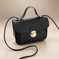 Women's envelope crossbody bag in black on a warm ivory/taupe studio background