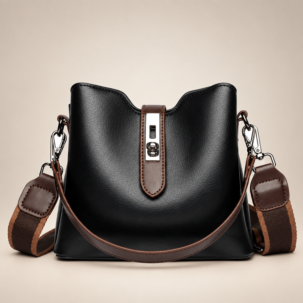 Black bucket bag with brown straps and silver hardware on a warm ivory studio background