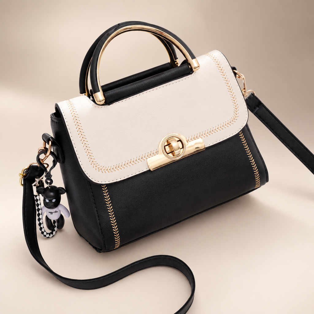 White And Black colour-block embroidered crossbody bag with black body, white flap, top handle and key charm on a warm ivory and taupe studio background
