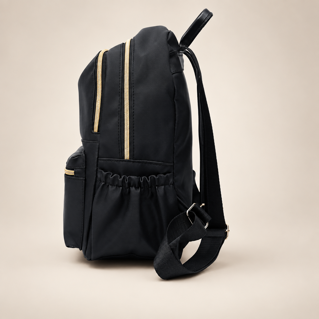 Black waterproof school backpack, side view, on a warm ivory/taupe studio background