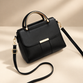 Women's structured ring-handle bag in black on a warm ivory/taupe studio background