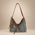 Grey woven shoulder bag with brown trim and tassels on a warm ivory studio background