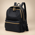 Black waterproof school backpack, front view, on a warm ivory/taupe studio background