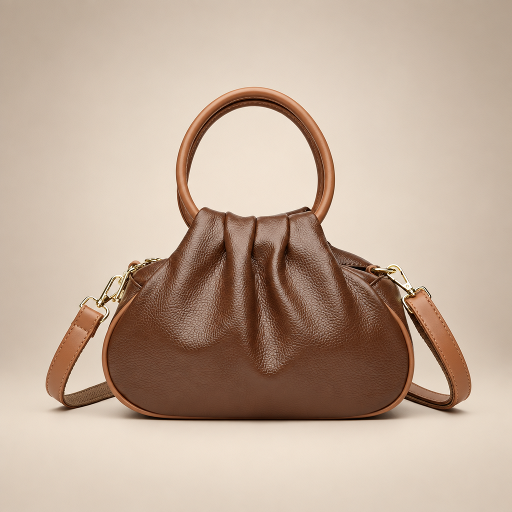 Brown pleated bag with tan round handles on a warm ivory studio background