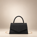 Black small square PU handbag with a top handle and chain strap on a warm ivory studio background