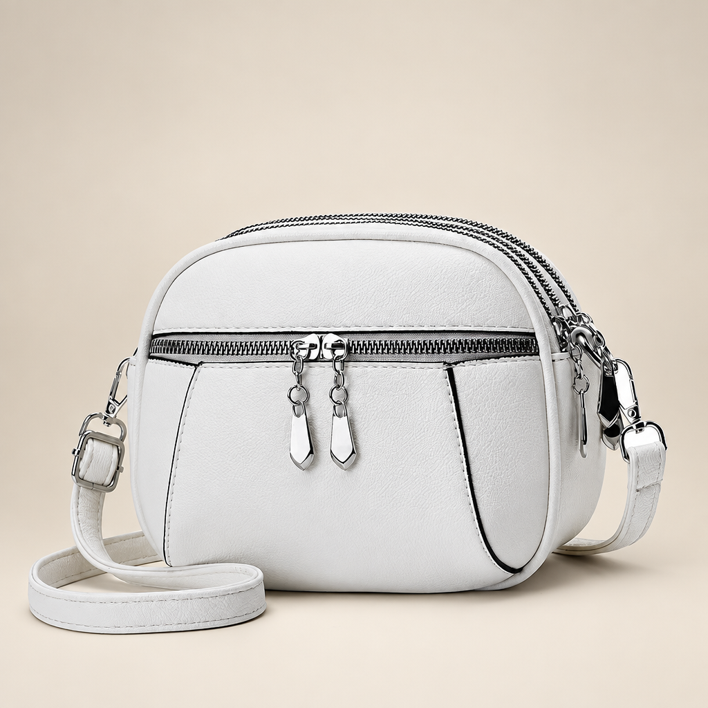 Small round crossbody bag on a warm ivory studio background