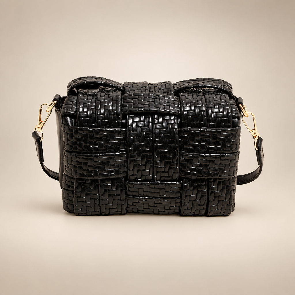 Black woven crossbody bag on a warm ivory studio background