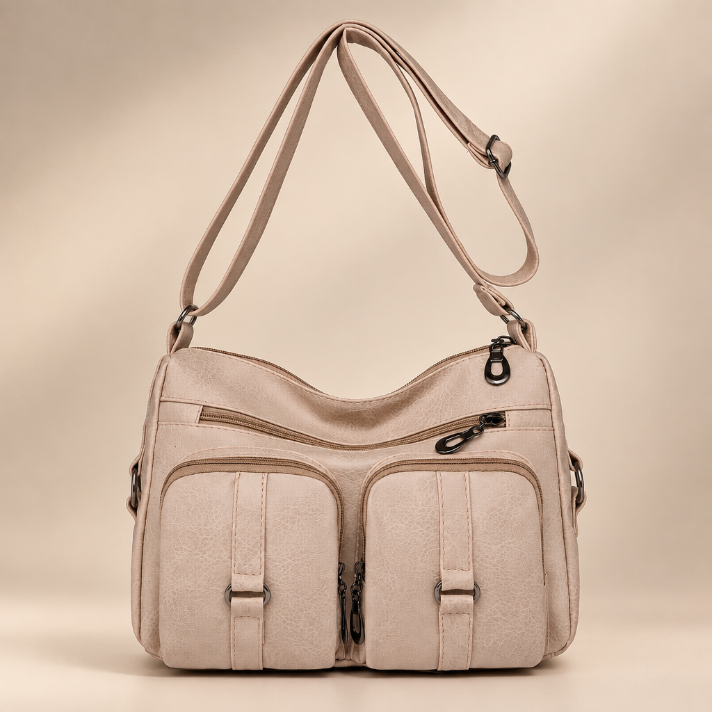 Creamy white PU crossbody bag with front zip and slip pockets on a warm ivory studio background