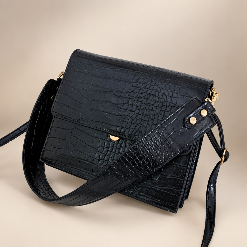 Black PU messenger bag photographed on a warm ivory studio background