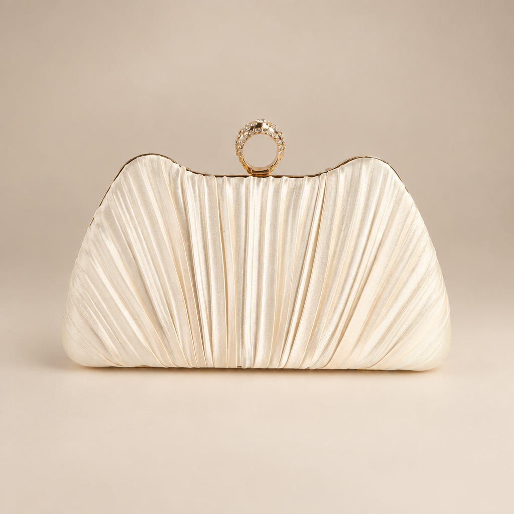 Champagne satin evening clutch with pleated front and jewelled ring clasp on a warm ivory studio background