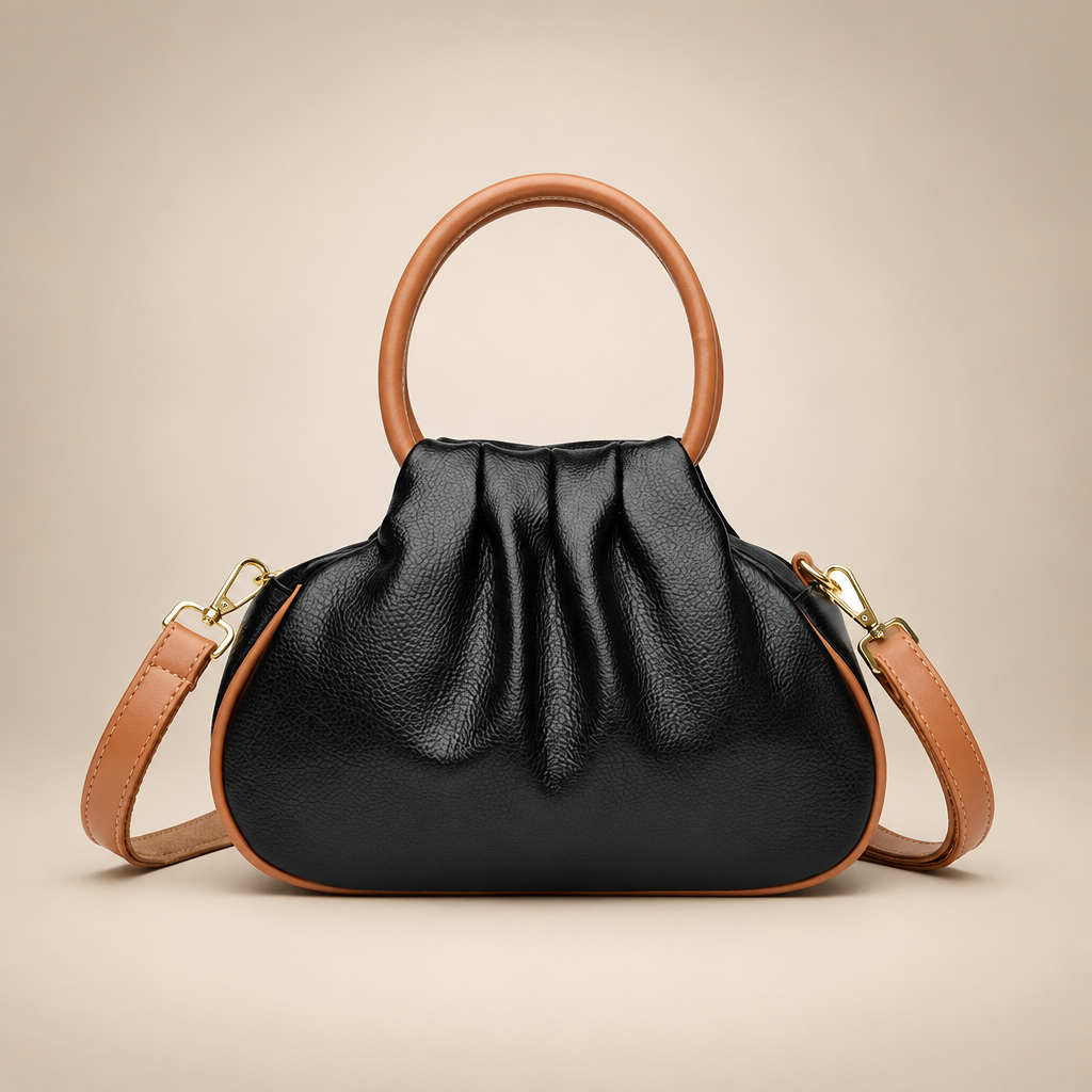 Black pleated bag with tan round handles on a warm ivory studio background