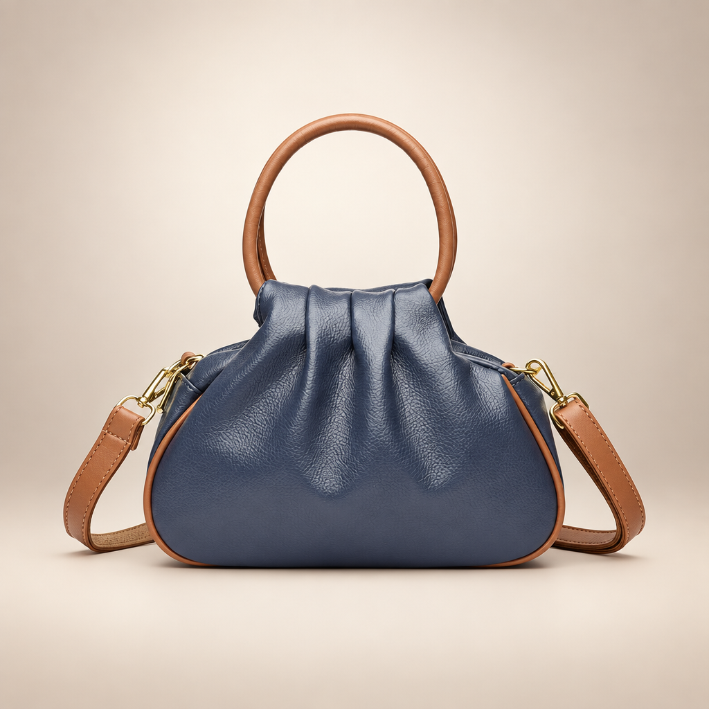 Blue pleated bag with tan round handles on a warm ivory studio background