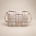 Cream woven crossbody bag on a warm ivory studio background