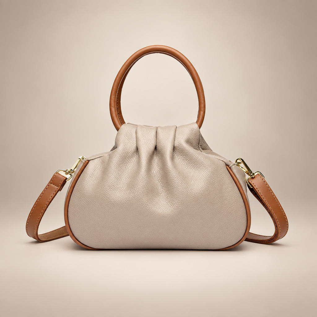 Beige pleated bag with tan round handles on a warm ivory studio background