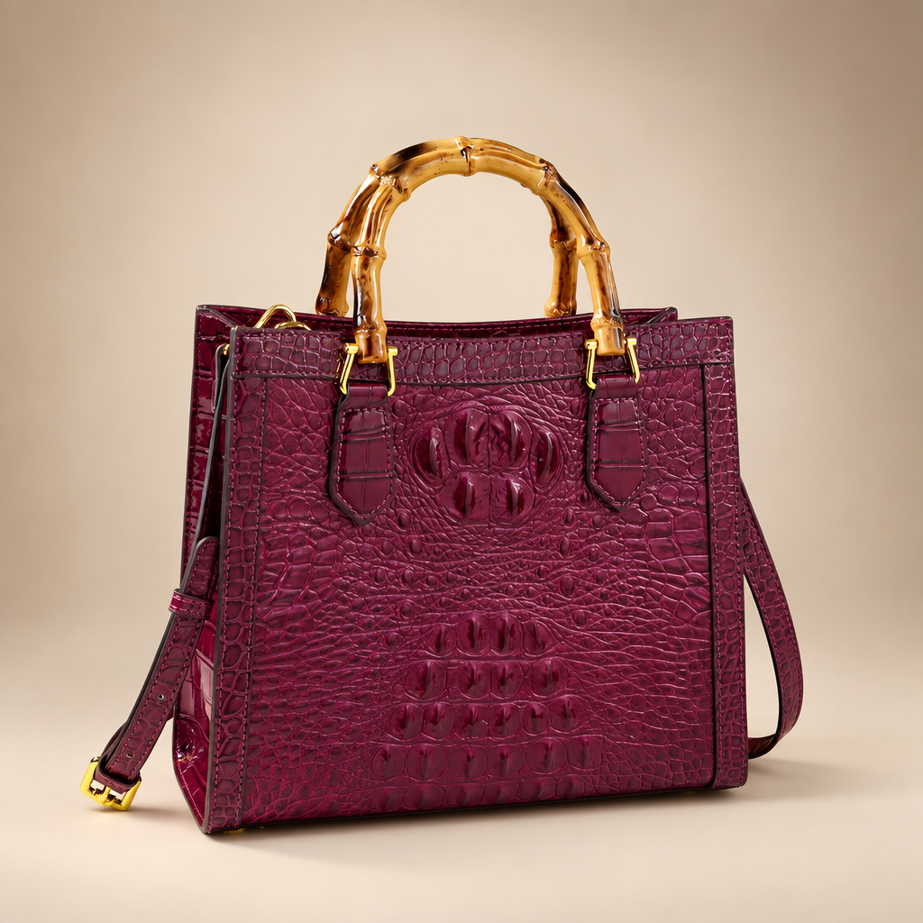 Burgundy croc-embossed handbag with bamboo-style handles on an ivory studio background