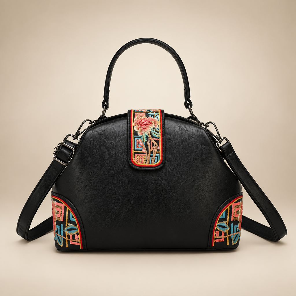 Black dome handbag with colourful floral panels on an ivory studio background