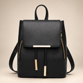 Women's flap backpack in black on a warm ivory/taupe studio background