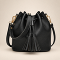 Black tassel drawstring bucket bag on a warm ivory studio background