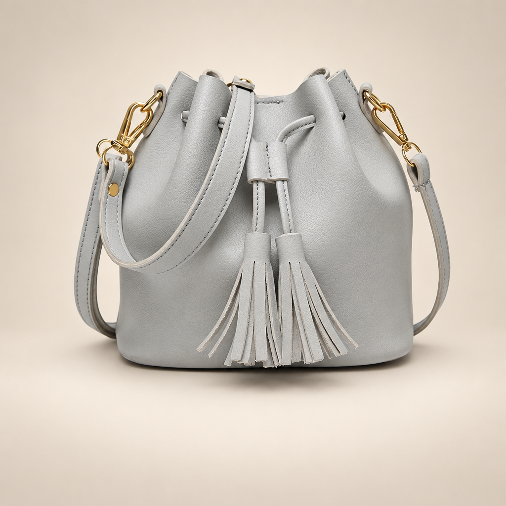 Light grey tassel drawstring bucket bag on a warm ivory studio background