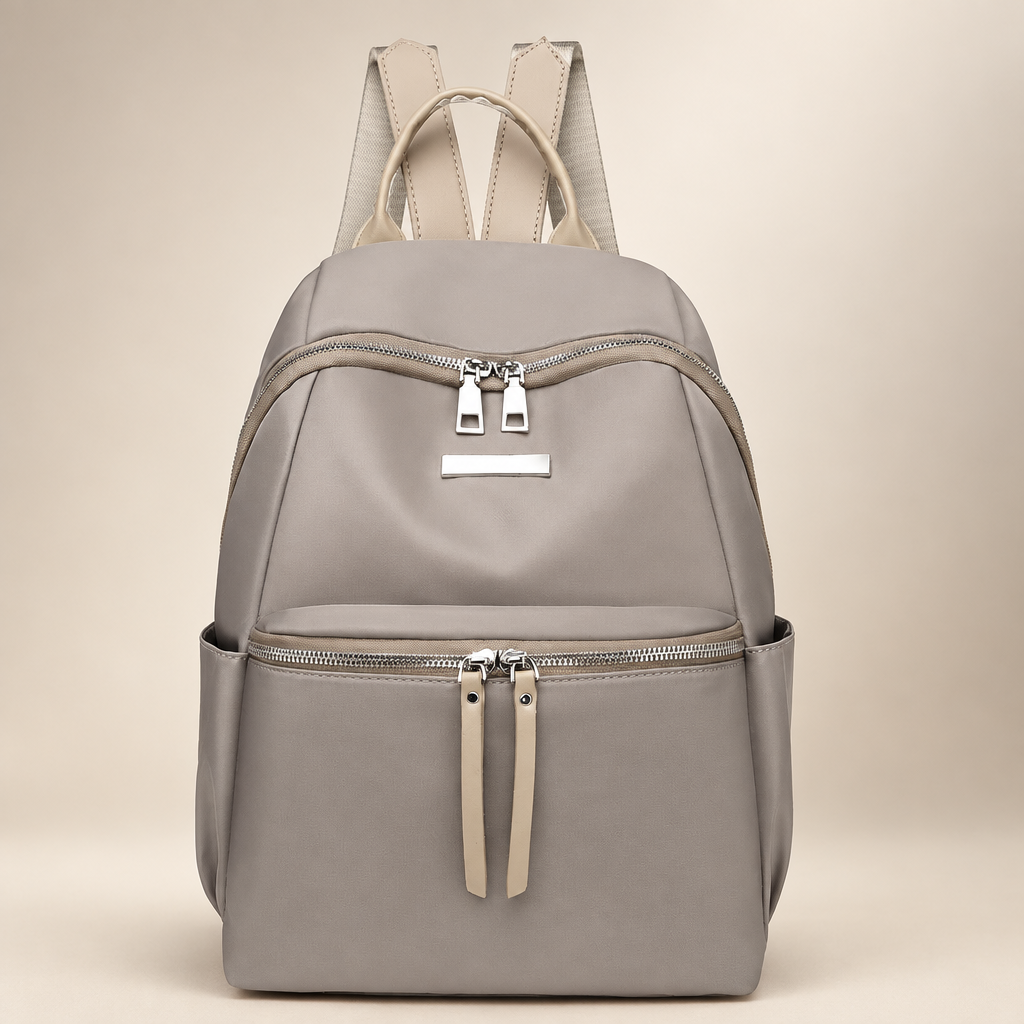 Taupe Oxford backpack with front zip pockets on a warm ivory studio background