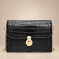 Black croc-embossed chain bag on a warm ivory studio background