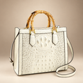 Ivory croc-embossed handbag with bamboo-style handles on an ivory studio background