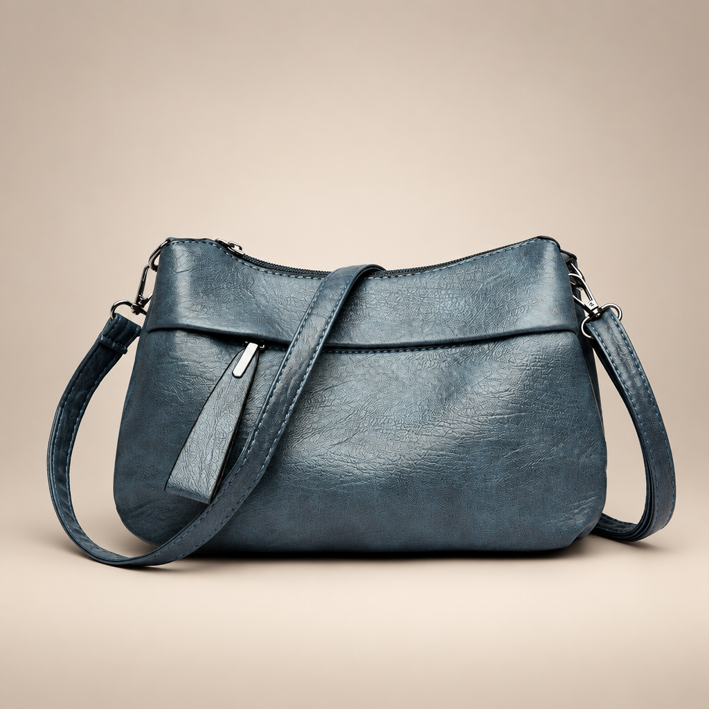 Blue-grey textured shoulder bag on a warm ivory studio background