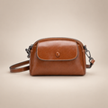 Brown mini shoulder bag with button flap, front view on a warm ivory studio background