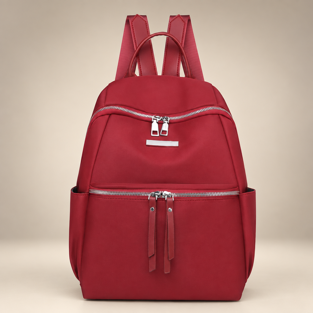 Red Oxford backpack with front zip pockets on a warm ivory studio background