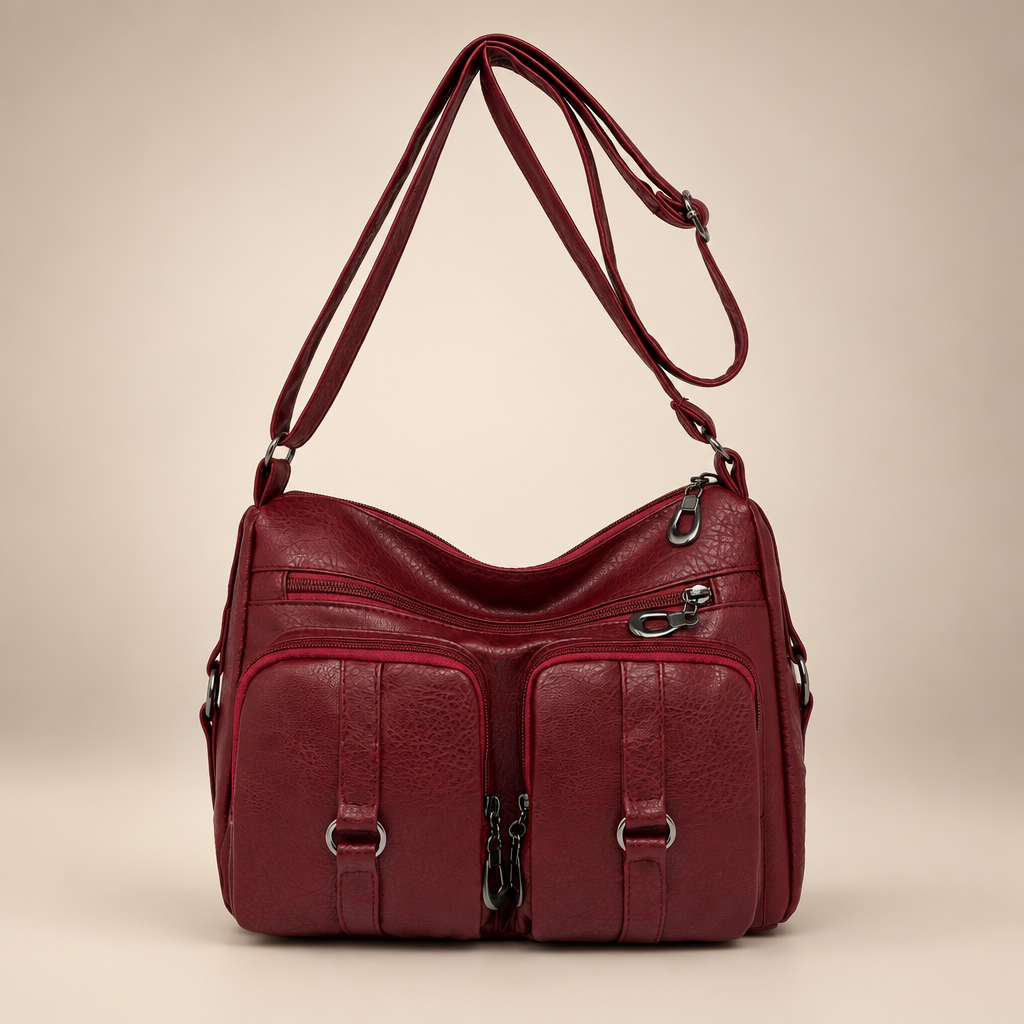 Red PU crossbody bag with front zip and slip pockets on a warm ivory studio background