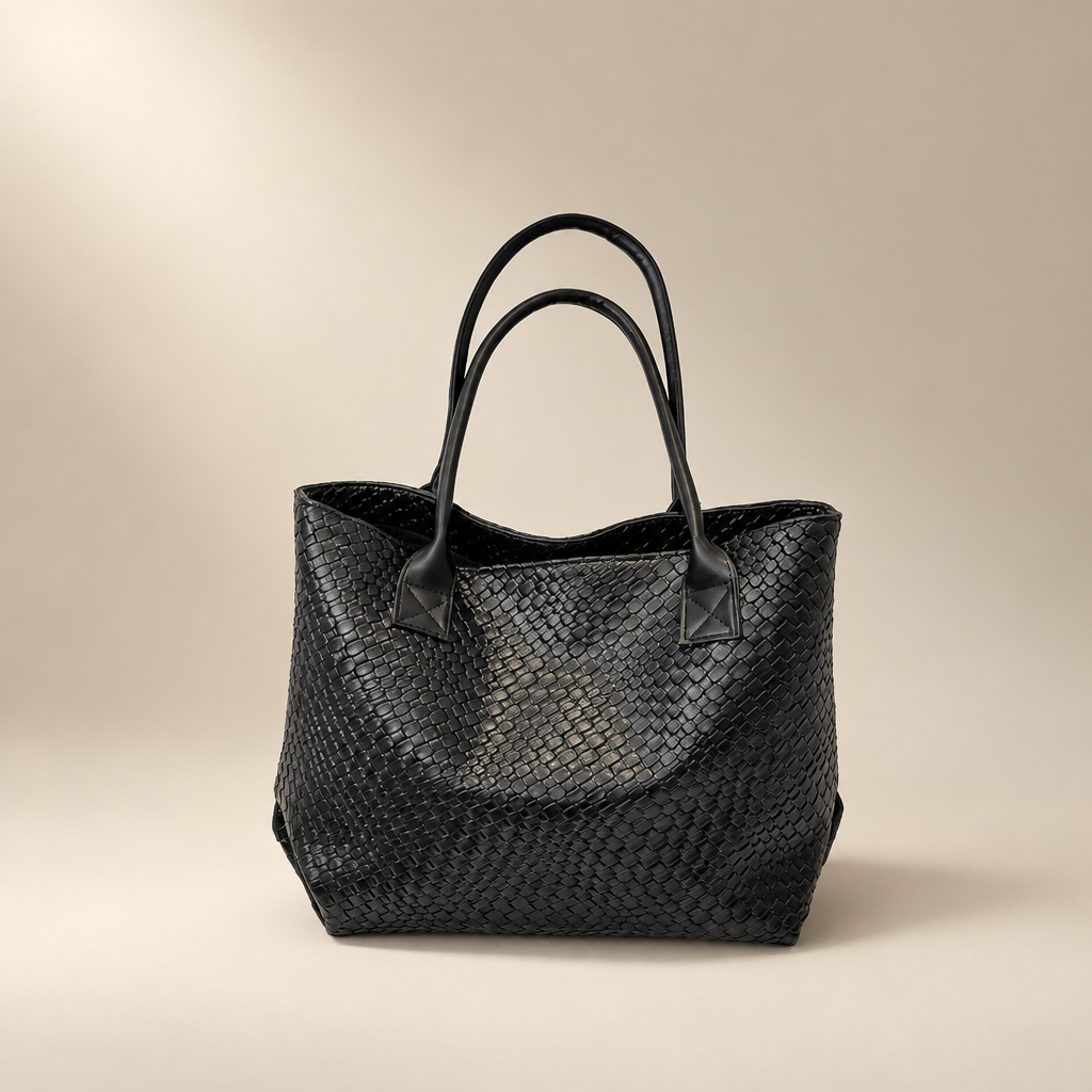 Black woven PU shoulder bag with double straps on a warm ivory and taupe studio background
