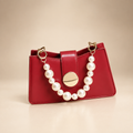 Red bag with pearl bead handle and gold-tone clasp on warm ivory studio background