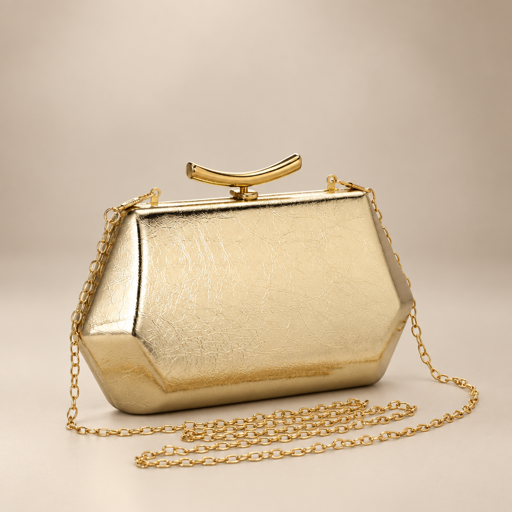 Gold faceted clutch with chain strap on warm ivory studio background