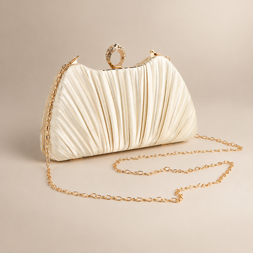 Champagne satin evening clutch with jewelled ring clasp and gold-tone chain on a warm ivory studio background