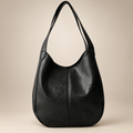 Vintage women's shoulder bag in black on a warm ivory/taupe studio background
