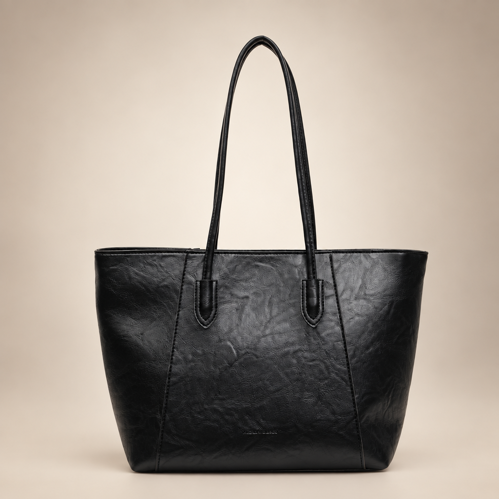 Black PU tote bag photographed on a warm ivory studio background