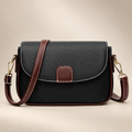 Women's small flap crossbody bag in black on a warm ivory/taupe studio background