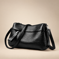 Black textured shoulder bag on a warm ivory studio background