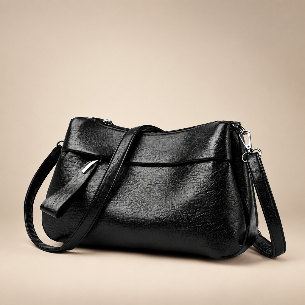 Black textured shoulder bag on a warm ivory studio background