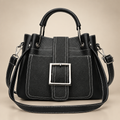 Black buckle handbag on a warm ivory studio background